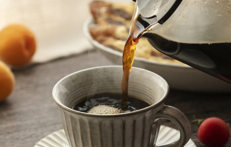 Person pouring a hot cup of coffee